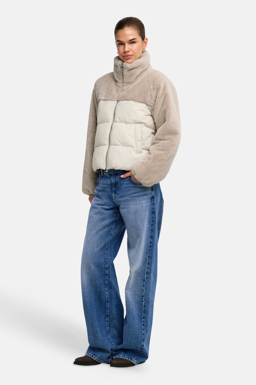 Doudoune gris clair avec manches et col en fausse fourrure teddy de ONLY®, panneau central plissé crème, fermeture éclair devant, le modèle porte un jean large bleu
