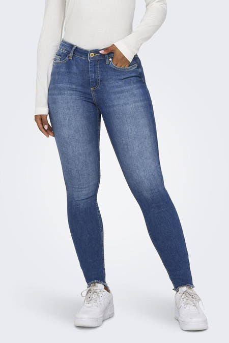 Jean skinny bleu d'ONLY, avec une main dans la poche et porté avec un t-shirt blanc.