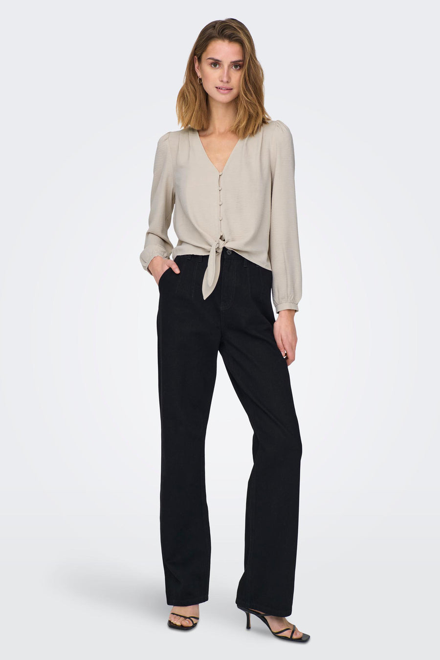 Grijze blouse van ONLY, geknoopt aan de voorkant, gecombineerd met zwarte pantalon en hakken.
