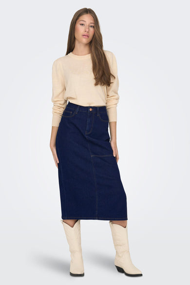 Denim rok van JDY met een donkerblauwe kleur en een midi-lengte, gecombineerd met crème laarzen en een trui.

