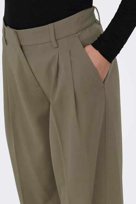 Pantalon gris d'ONLY, avec des plis et une main dans la poche.