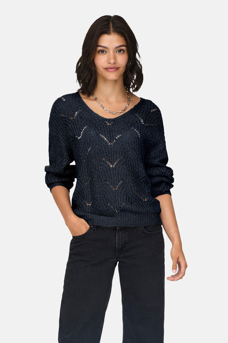 T-shirt bleu à col V de JDY, avec un motif ajouré et des manches longues, associé à un jean noir et une chaîne d'argent.