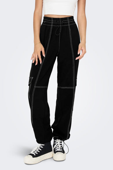 Pantalon de travail noir ONLY, avec des coutures contrastantes et porté avec un haut blanc et des baskets à plateforme.