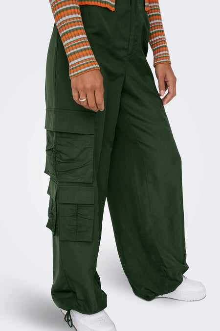 Pantalon de travail vert ONLY, avec des poches sur les poches et combiné à une chemise rayée et des baskets blanches.