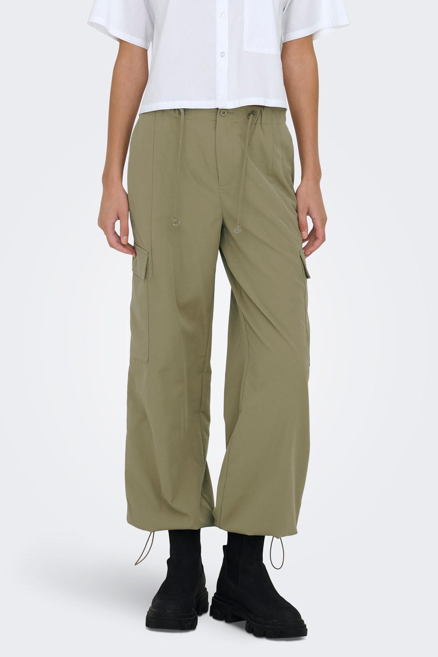 Pantalon de travail vert ONLY, associé à des bottes noires et un t-shirt blanc.