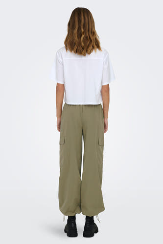 Pantalon de travail vert ONLY, avec des larges large et des poches visibles, associé à une chemise blanche et des bottines noires.