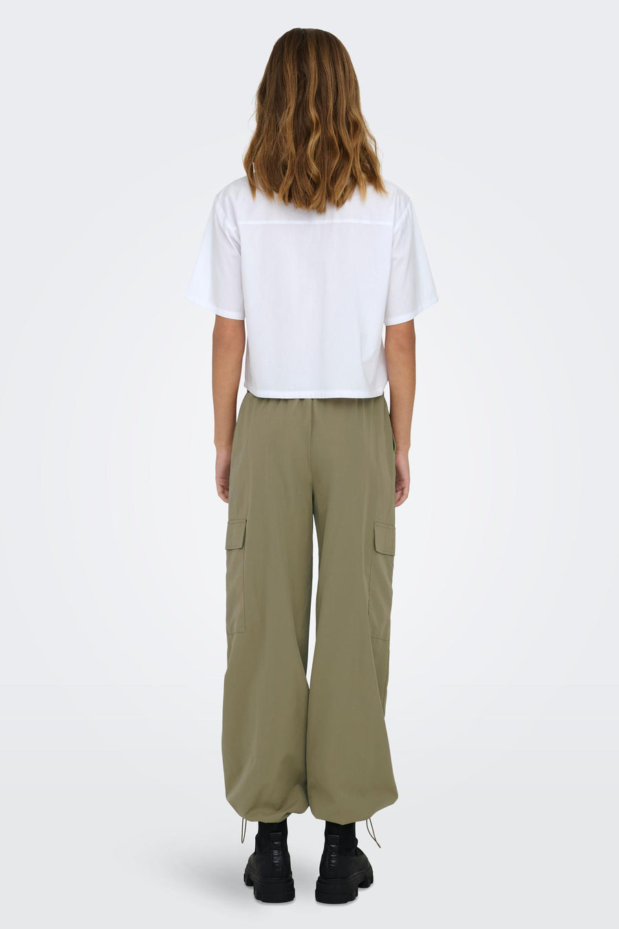 Pantalon de travail vert ONLY, avec des larges large et des poches visibles, associé à une chemise blanche et des bottines noires.