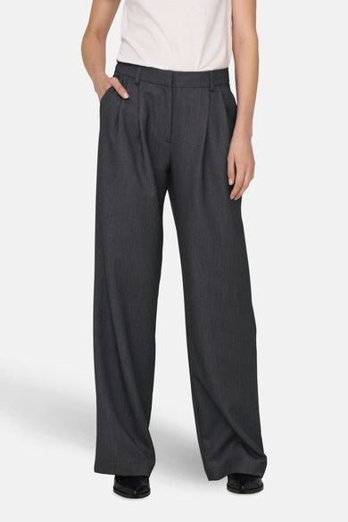 Pantalon gris de costume d'ONLY, avec des poches larges et une main dans la poche.