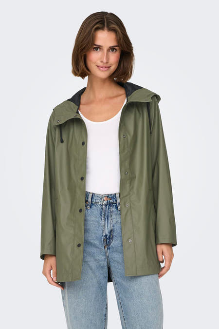 Veste de pluie verte ONLY, avec des manches longues, portée ouverte sur une chemise blanche et un jeans bleu.