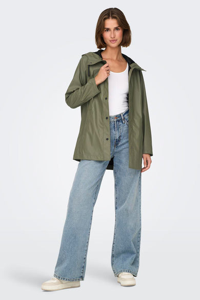 Groene regenjas van ONLY, met lange mouwen, open gedragen over een wit hemd en blauwe jeans.