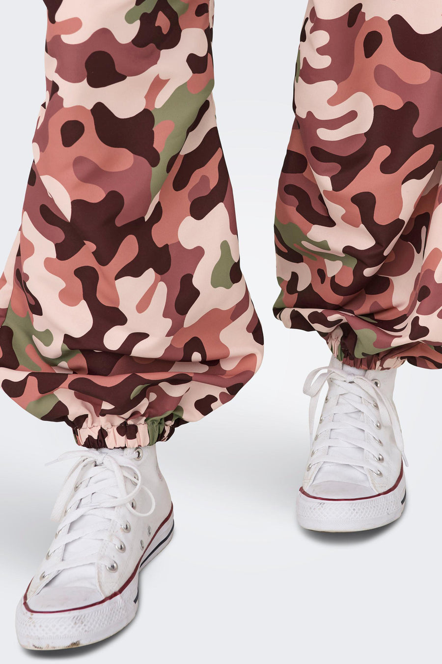 Pantalon camouflage rose de NEON & NYLON, associé à des baskets blanches avec l lacets.