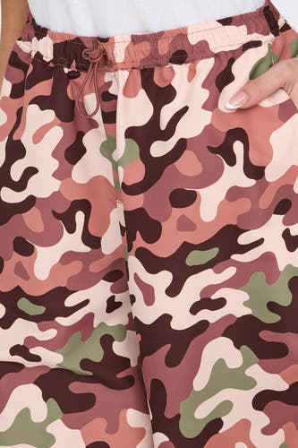 Pantalon coupé avec imprimé camouflage de NEON & NYLON, dans des teintes de rose, marron et vert, plus des détails d'une chemise blanche.
