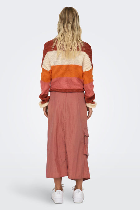 Robe rose de NEON & NYLON, trois quarts de longueur, avec des poches et portée avec un pull rayé.