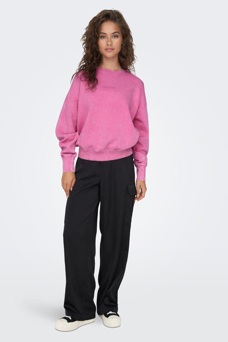 Pull-over rose ONLY®, avec des manches longues et un col rond, porté avec un pantalon noir.
