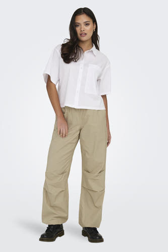 Beige broek van ONLY, met wijde pijpen en gedragen met een wit overhemd en zwarte schoenen.