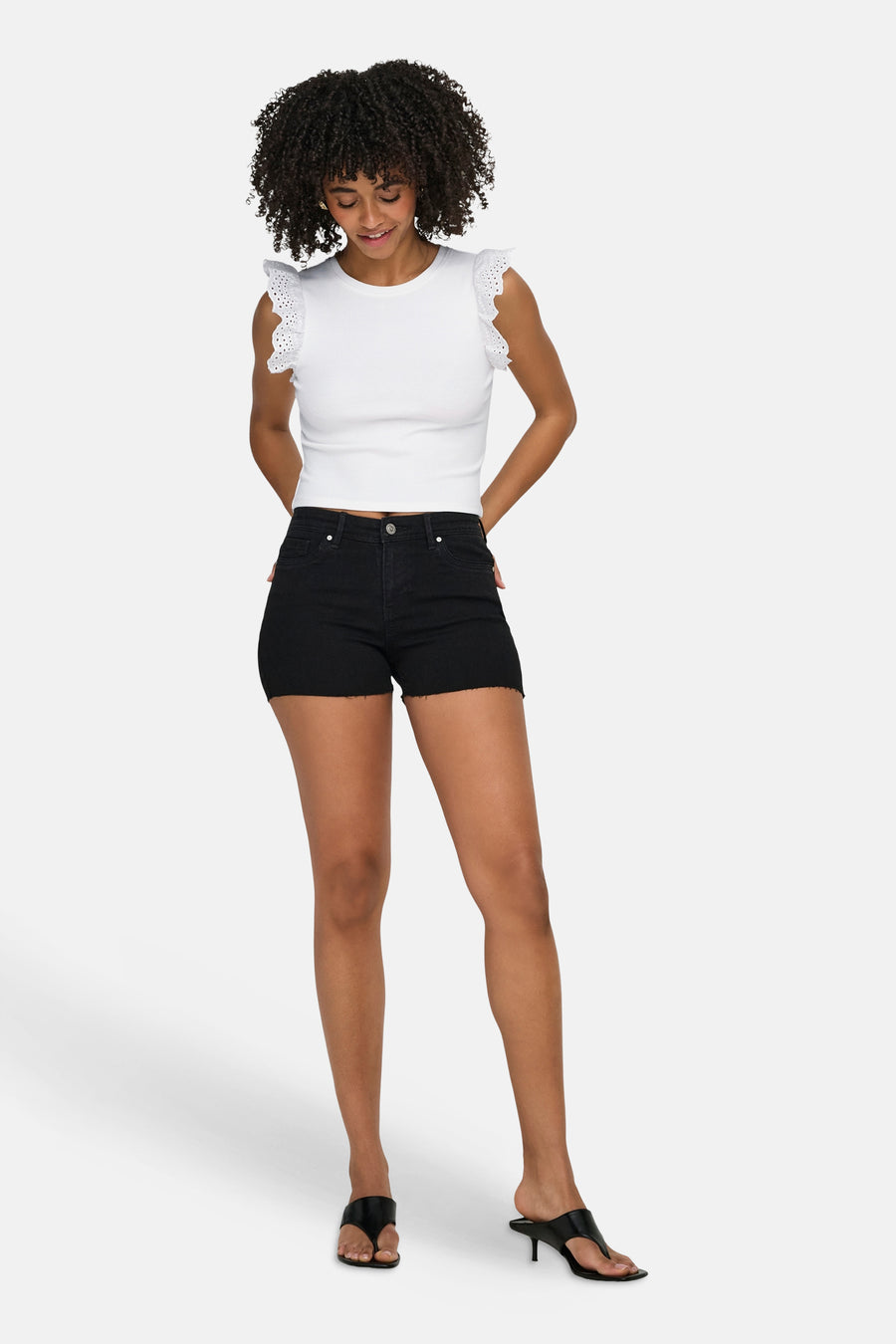 Wit geribbeld T-shirt van ONLY met ruchesmouwen met perforaties, gedragen met zwarte denim shorts en hakken.