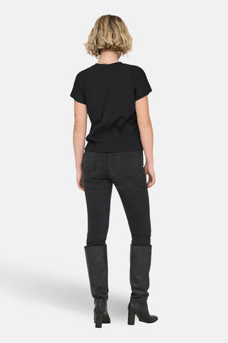 T-shirt noir à manches courtes ONLY®, vu de dos, combiné avec un jean noir et des bottes en cuir à talons.