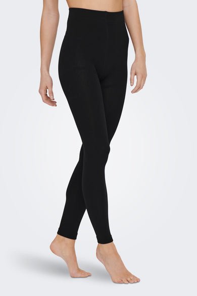Legging noire ONLY, lisse et ajustée, portée par un modèle pieds pieds un fond fond blanc..