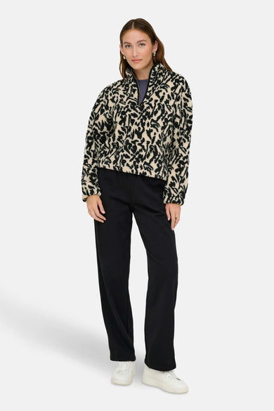 Fleece noir ONLY, avec un imprimé animal noir et beige, porté avec un pantalon noir et des baskets blanches.