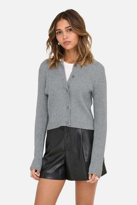 Veste grise d'ONLY, avec fermeture à boutons, portée sur une chemise blanche et associée à des short en cuir noirs.