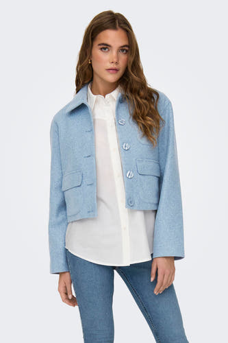 Blouson court bleu de JDY, avec des manches longues et associé à des jeans et des bottes noires.
