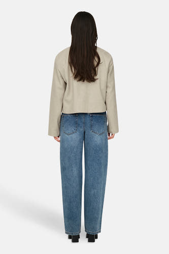 Manteau court beige de JDY, vu de de derrière, associé à un jean bleu et des baskets noires.