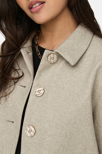 Manteau court beige de JDY, avec fermeture à boutons et chaîne dorée.