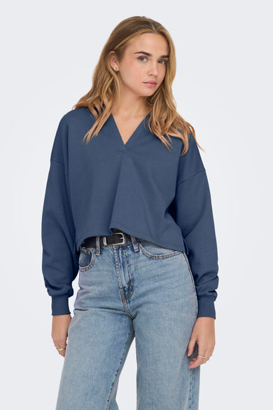 Pull-over bleu de ONLY, vu de de l'arrière avec des jeans légers à larges poches.