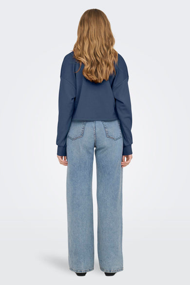 Blauwe sweater van ONLY, gezien vanaf de achterkant, met lichte jeans met wijde pijpen.