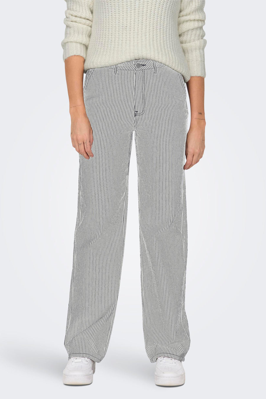 Pantalon blanc de ONLY®, avec un motif rayé fin, associé à une chemise tricotée et des baskets blanches.