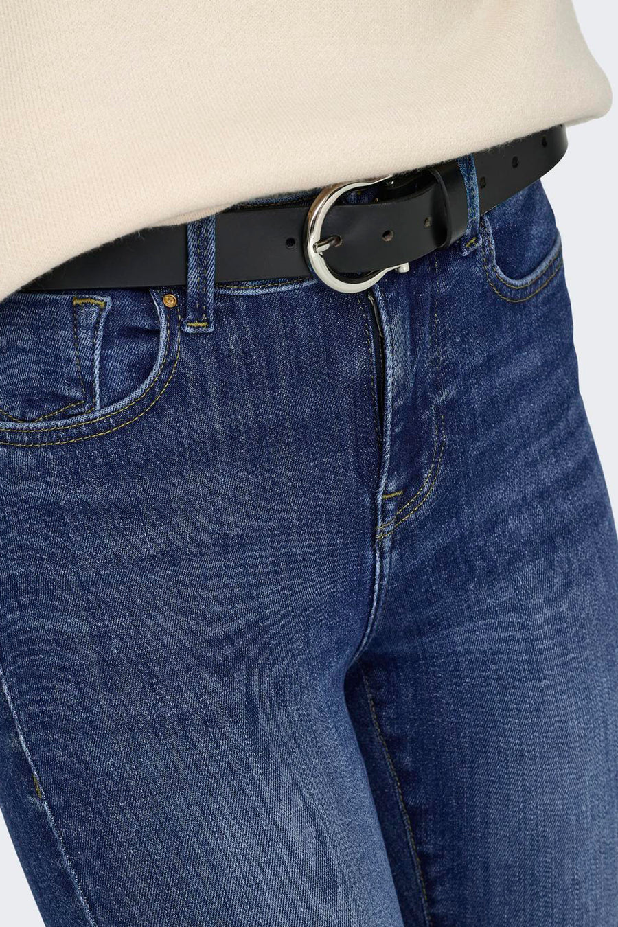 Gros plan sur un jean skinny bleu foncé de la marque ONLY, avec des surpiqûres jaunes, une ceinture noire et une boucle argentée.