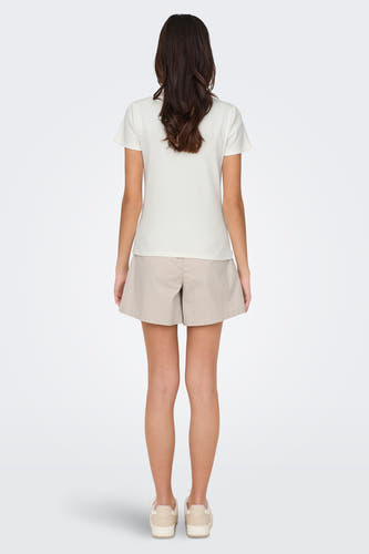 T-shirt blanc à manches courtes de JDY, vu de derrière, associé à des short beige et des baskets coordonnées.