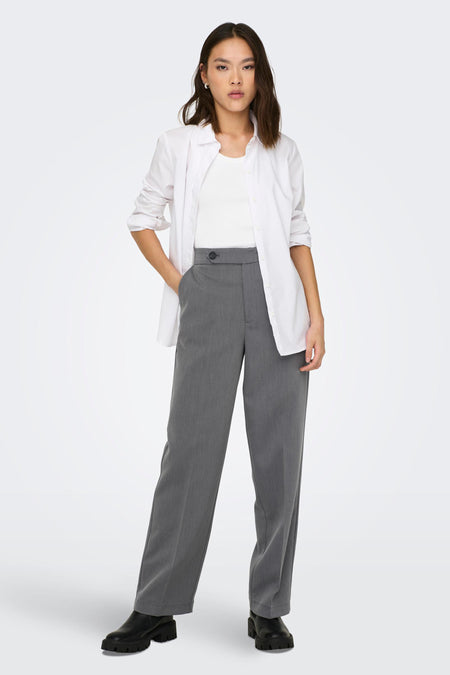 Pantalon gris d'ONLY, avec un nœud, associé à une chemise blanche et des chaussures noires à semelles épaisses.