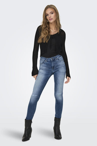 Gilet noir de ONLY, porté sur une chemise noire avec des jeans bleus et des bottes noires.