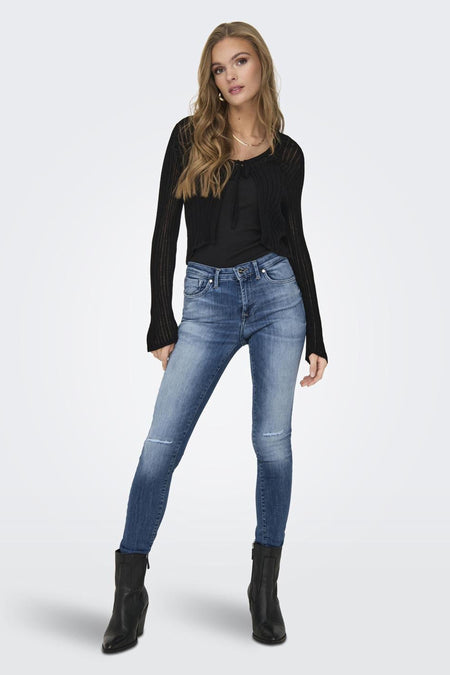 Gilet noir de ONLY, porté sur une chemise noire avec des jeans bleus et des bottes noires.