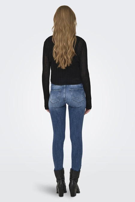 Cardigan noir d'ONLY, avec des manches longues, associé à un jeans bleu et des bottes noires.