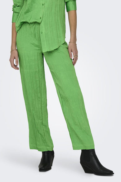 Pantalon vert de ONLY avec une texture froissée, associé à des bottes noires et des bijoux en or.