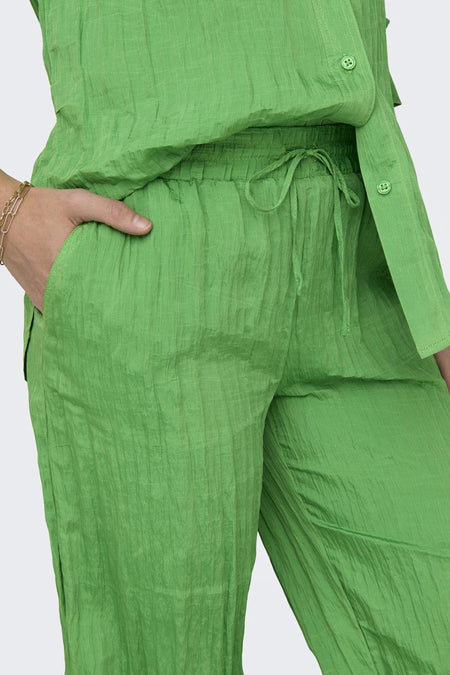 Pantalon vert de ONLY, avec une ceinture à la taille et une main dans la poche.