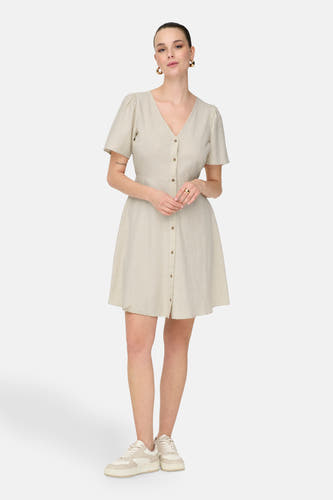 Robe écru à manches courtes de ONLY, avec une fermeture à boutons et portée avec des baskets blanches.
