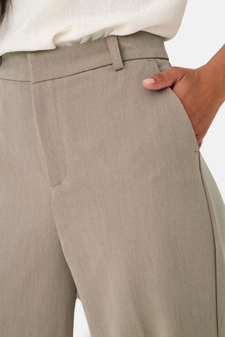 Grijze damesbroek met hand in de zak.