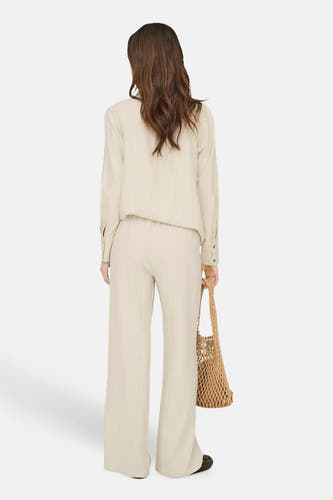 Pantalon beige de JDY coupe ample, porté avec une chemise assortie et un sac en filet, vue de dos.