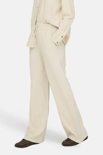 Pantalon beige de JDY, en tissu aspect lin, avec taille élastique, cordon de serrage et jambes larges, porté avec une chemise assortie.