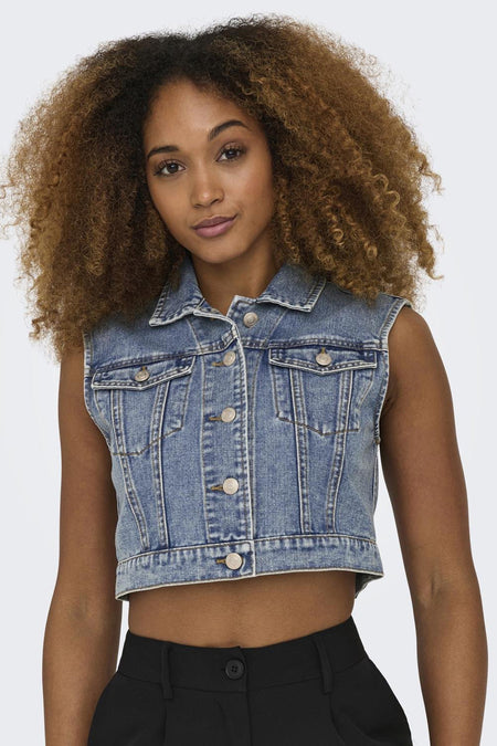 Veste en denim bleu moyen de ONLY®, avec boutons, poches et coupe ajustée, portée par un mannequin aux cheveux bouclés