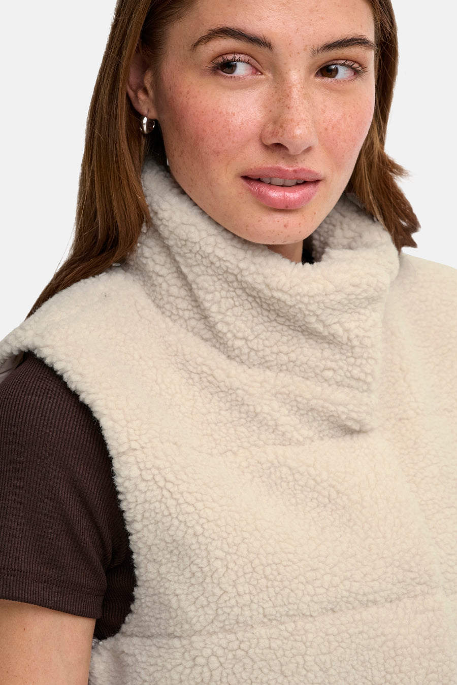 Doudoune sans manches couleur crème en tissu de peau de mouton avec col montant, de la marque ONLY®, portée sur un pull côtelé marron foncé, gros plan de l'avant