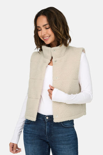 Gilet écru d'ONLY, avec des boutons-pression et un col, associé à une chemise blanche à manches longues et un jeans foncé.