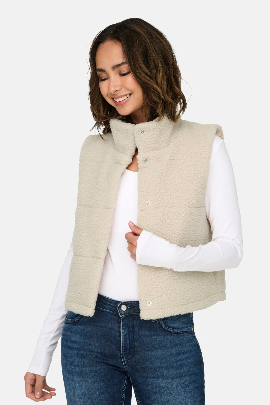 Gilet écru d'ONLY, avec des boutons-pression et un col, associé à une chemise blanche à manches longues et un jeans foncé.