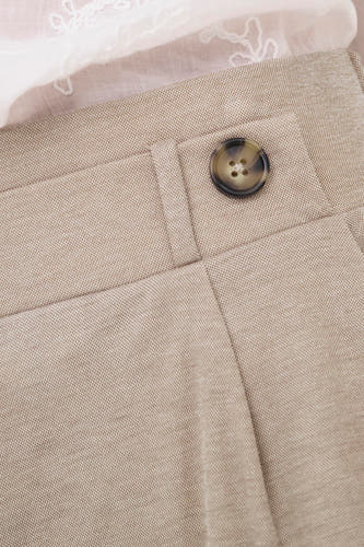 Pantalon beige de JDY avec un bouton marron, une texture fine et un haut en dentelle blanche par-dessus.