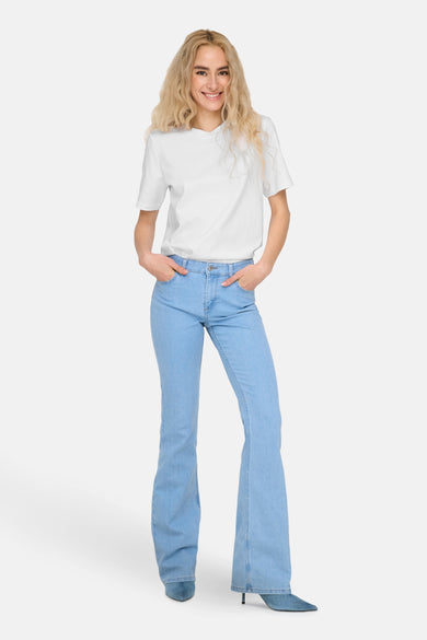 T-shirt blanc à manches courtes de ONLY, porté avec un pantalon de travail bleu et des bottes.