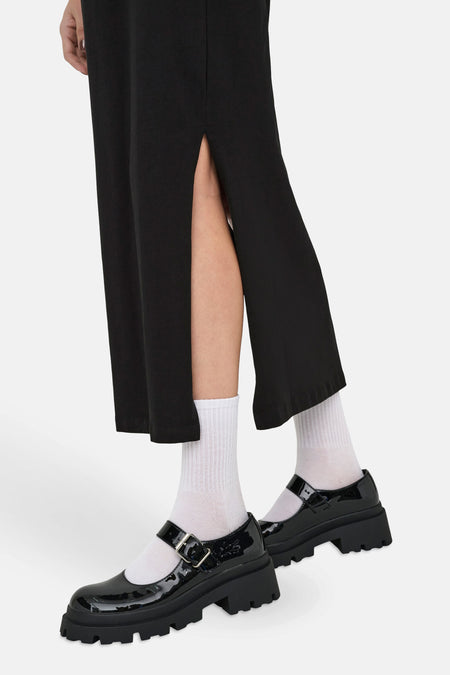 Robe noire à manches courtes de JDY, avec une fente latérale et associée à des chaussettes blanches et des chaussures Mary Jane noires.