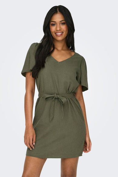 Robe verte à manches courtes de JDY, avec une ceinture et portée avec des baskets blanches.